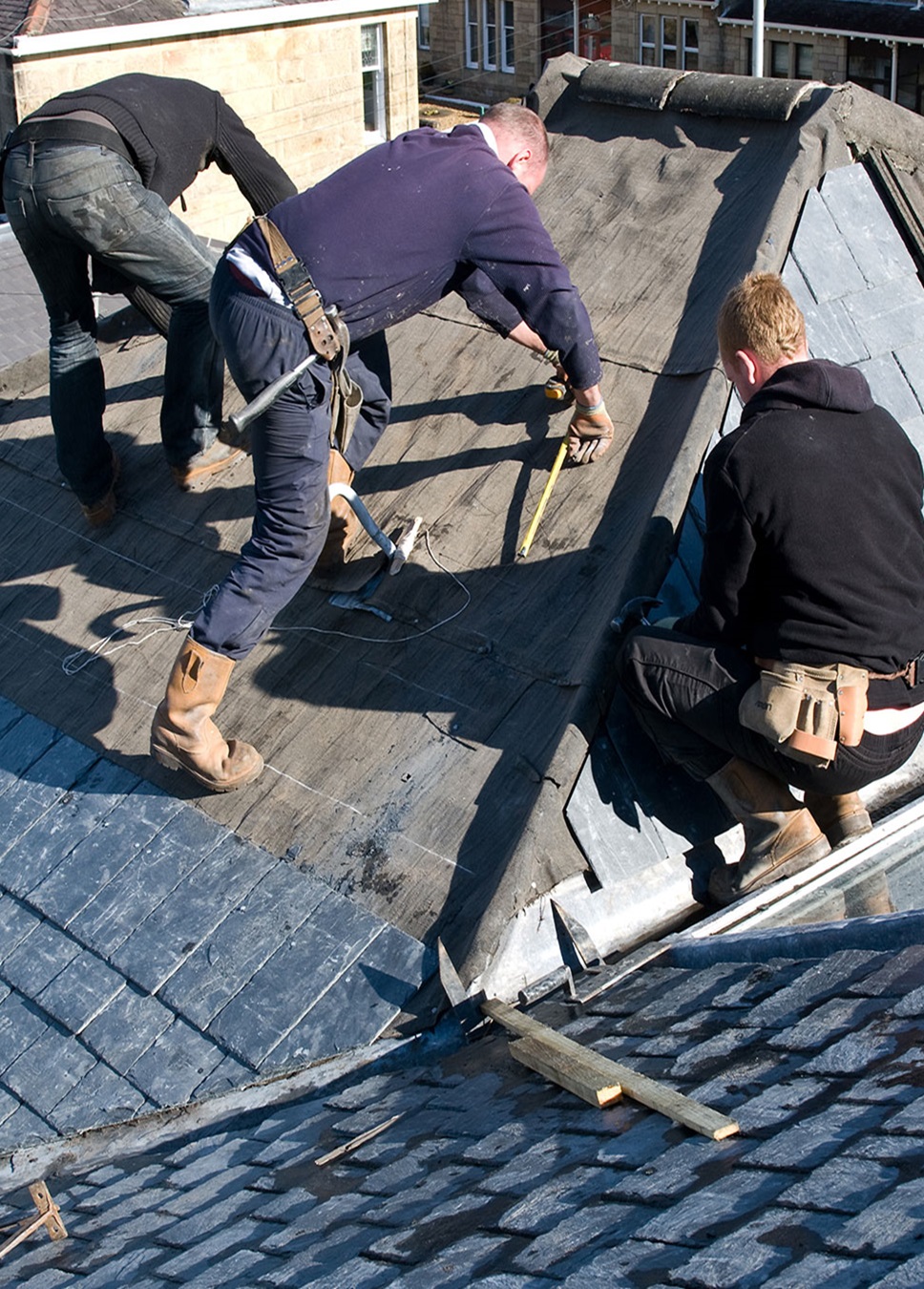 Roof Repairs Romsey Workers from Southampton Roofing performing repairs on a house exterior as part of roof repair Ramsey, with ongoing construction.